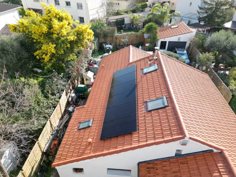 Vue aérienne de panneaux solaires noirs posés sur une toiture en tuiles avec fenêtres de toit à Hyères