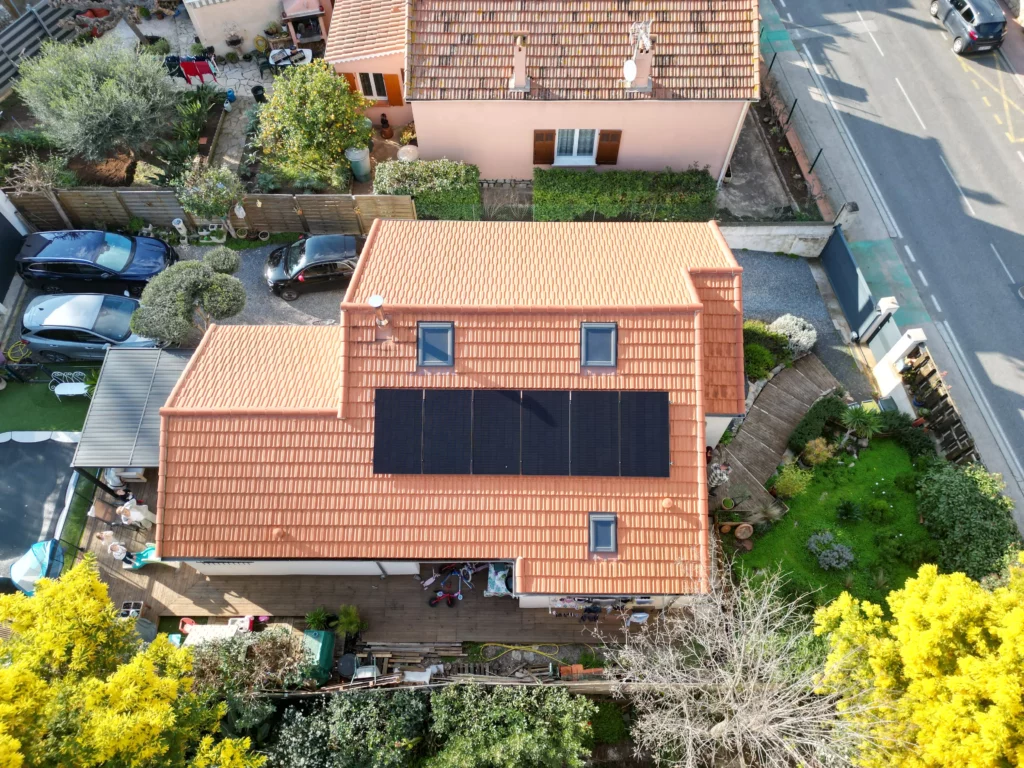 Vue latérale de panneaux photovoltaïques noirs posés sur toiture rouge à Hyères