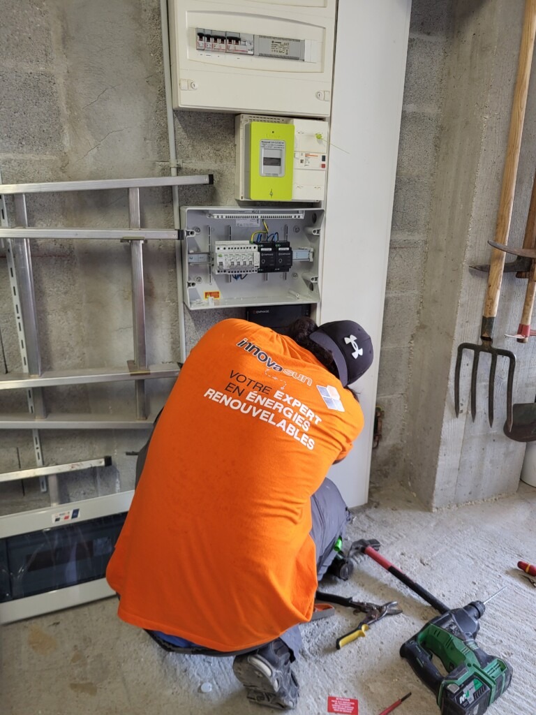 Technicien Innovasun installant un système photovoltaïque avec micro-onduleurs et coffret électrique