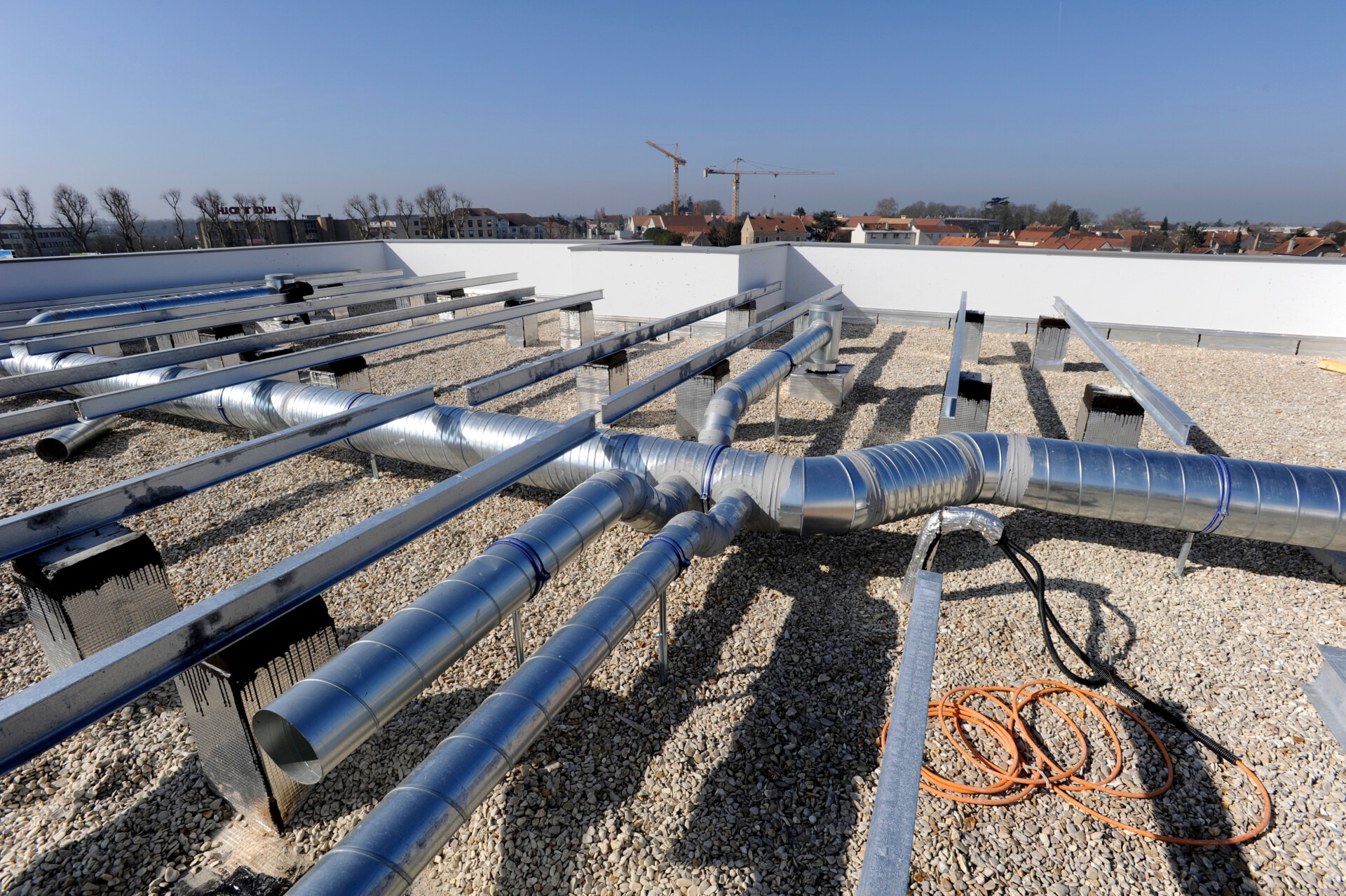 Gaines de ventilation collective en acier galvanisé installées sur le toit plat d'un immeuble en copropriété