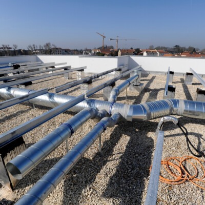 Gaines de ventilation collective en acier galvanisé installées sur le toit plat d'un immeuble en copropriété